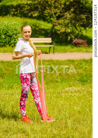 Girl doing exercises outdoor, using resistance fit band. Girl doing exercises outdoor, using resistance fit band. 124197314