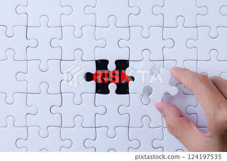 Risk Management and Identification Concept. A hand places a puzzle piece into a nearly complete puzzle, revealing the word Risk in red, process of identifying and managing risks within complex systems Risk Management and Identification Concept. A hand places a puzzle piece into a nearly complete puzzle, revealing the word Risk in red, process of identifying and managing risks within complex systems 124197535