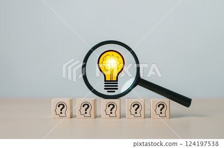 Innovation and Problem Solving Concept. Magnifying glass focuses on light bulb icon above wooden blocks with question marks, creative solutions, insight, process of finding answers to complex problems Innovation and Problem Solving Concept. Magnifying glass focuses on light bulb icon above wooden blocks with question marks, creative solutions, insight, process of finding answers to complex problems 124197538