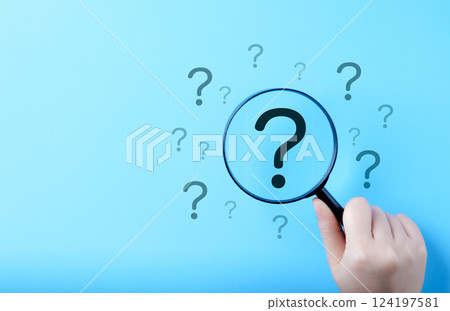 Question Mark and Root Cause Analysis Concept. A hand holding a magnifying glass over a large question mark surrounded by smaller ones on a blue background, symbolizing analysis and problem-solving. 124197581