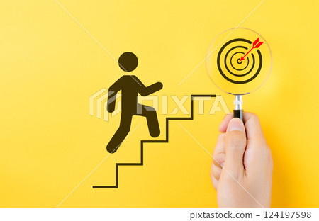 Success and goal achievement concept. A person climbing stairs toward target in a magnifying glass, progress, determination, and goal achievement in personal or business contexts. Steps for goal, Success and goal achievement concept. A person climbing stairs toward target in a magnifying glass, progress, determination, and goal achievement in personal or business contexts. Steps for goal, 124197598