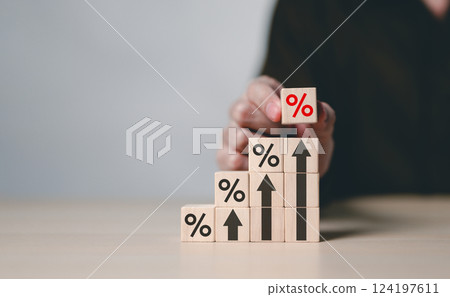 Interest Rate and Growth Concept. Wooden blocks with percentage symbols and upward arrows stacked progressively, representing interest rates, financial growth, and dividends in the economy. 124197611