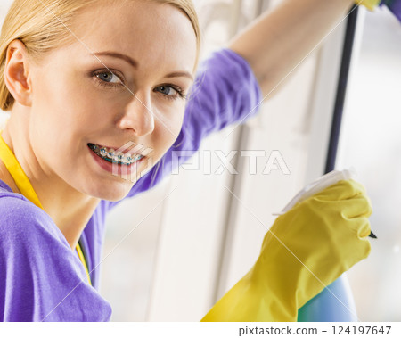 Girl cleaning window at home 124197647