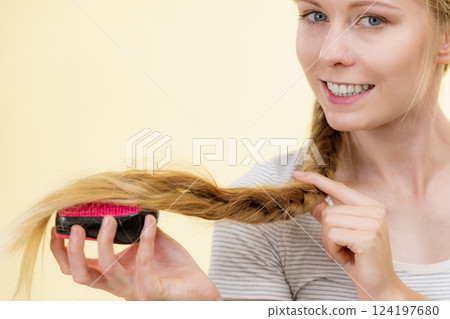 Blonde girl with long braid hair holds brush Blonde girl with long braid hair holds brush 124197680