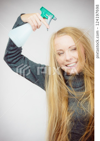 Female messy long hair holds spray bottle 124197698