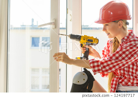 Woman using drill to fix or installing windows Woman using drill to fix or installing windows 124197717