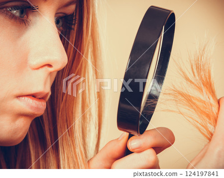 Sad woman looking at damaged hair ends. 124197841