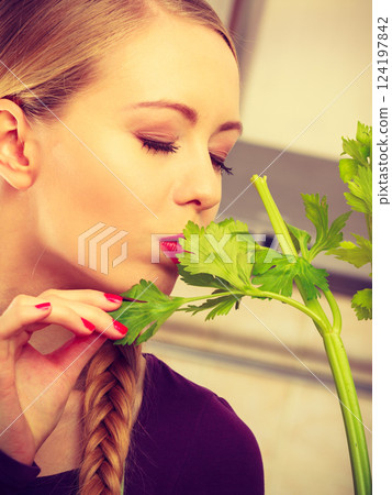Woman in kitchen holds green celery 124197842