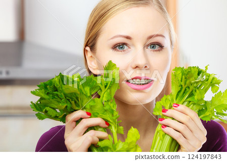 Woman in kitchen holds green celery 124197843