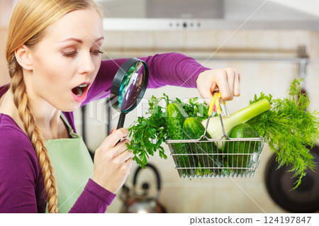 Woman looking through magnifier at vegetables basket Woman looking through magnifier at vegetables basket 124197847