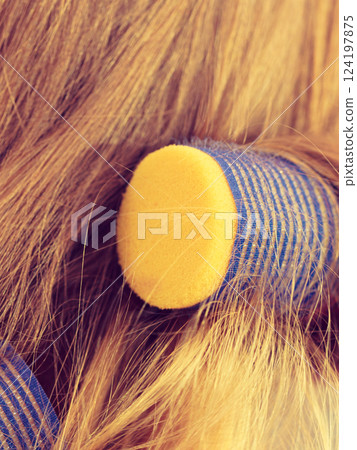 Woman curling her hair using rollers Woman curling her hair using rollers 124197875