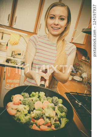 Woman cooking stir fry frozen vegetable on pan Woman cooking stir fry frozen vegetable on pan 124197937