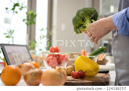 Middle woman cooking while looking at a tablet 124198257