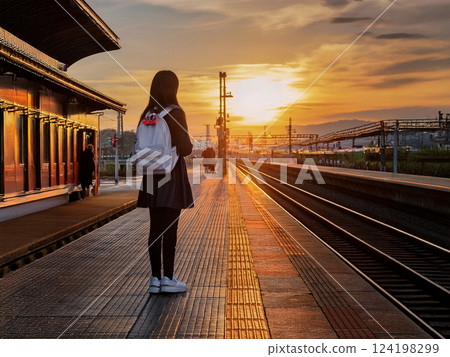 Students waiting for a train at an unmanned station at dusk 124198299