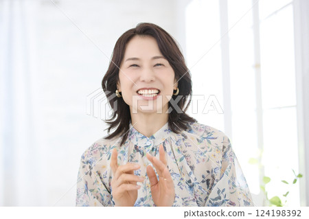 A smiling middle-aged woman wearing a floral blouse A smiling middle-aged woman wearing a floral blouse 124198392
