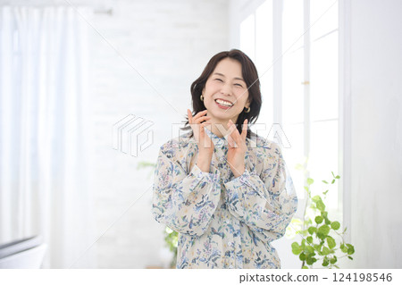 A smiling middle-aged woman wearing a floral blouse A smiling middle-aged woman wearing a floral blouse 124198546