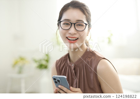 Young woman sitting in bed and looking at her smartphone Young woman sitting in bed and looking at her smartphone 124198822