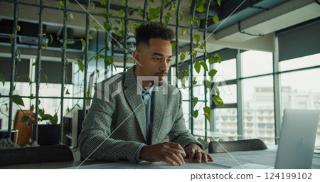 Focused businessman analyzing documents in modern office 124199102