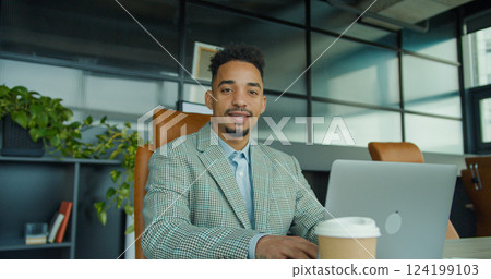 Confident businessman smiling while working in a modern office setting. 124199103