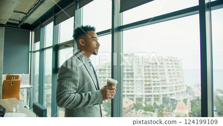 Businessman enjoying coffee by a panoramic window. Businessman enjoying coffee by a panoramic window. 124199109