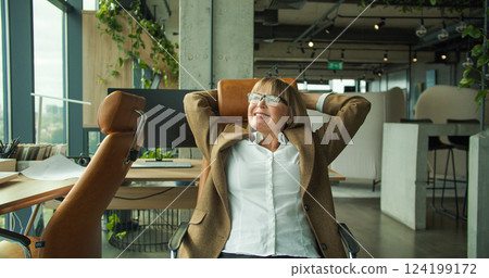 A businesswoman celebrating success by throwing papers in modern office with city view, showing joy and relief A businesswoman celebrating success by throwing papers in modern office with city view, showing joy and relief 124199172