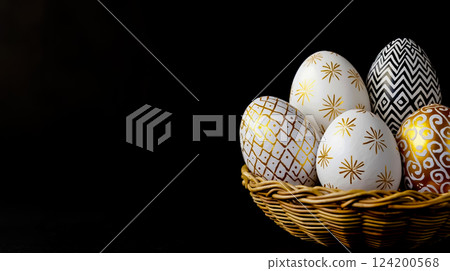 A basket filled with white and gold painted eggs on a black background A basket filled with white and gold painted eggs on a black background 124200568