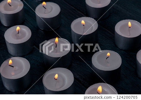 Tea light candles on a dark background, many lights in the dark 124200705