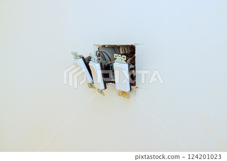 Three light switches are positioned in fresh wall, ready for electrical connection in home renovation Three light switches are positioned in fresh wall, ready for electrical connection in home renovation 124201023