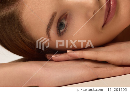 Close-up of young woman resting head on hand, demonstrating smooth skin and natural beauty. 124201303