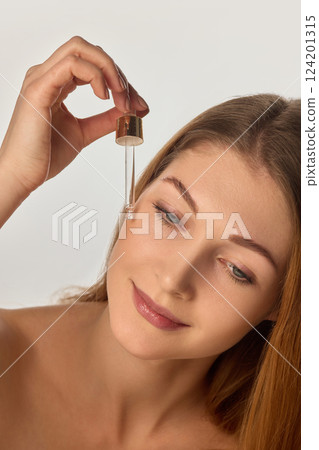 Portrait of young beautiful woman with smooth, clear skin, applying moisturizing rejuvenating facial serum against white background Portrait of young beautiful woman with smooth, clear skin, applying moisturizing rejuvenating facial serum against white background 124201315