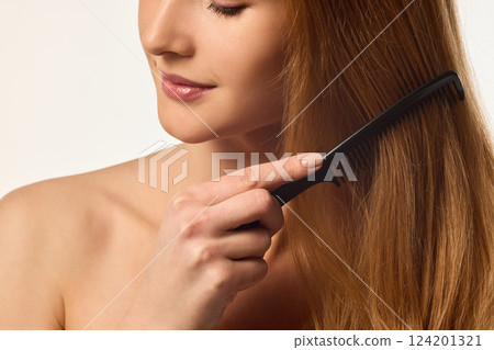 Close-up cropped image of woman brushing her golden hair with precision, highlighting hair wellness. Close-up cropped image of woman brushing her golden hair with precision, highlighting hair wellness. 124201321