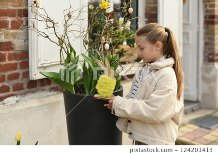Decorations on branches hanging eggs and a bunny and a girl 124201413