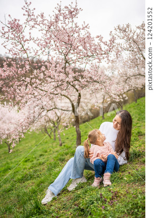 Young woman with little daughter in a blooming pink and white garden Petrin in Prague, spring time in Europe Young woman with little daughter in a blooming pink and white garden Petrin in Prague, spring time in Europe 124201552