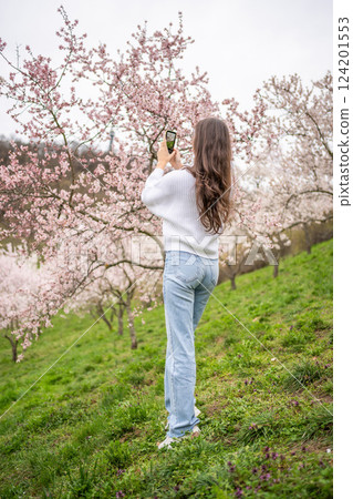 Lovely young woman taking photo of blooming pink and white garden Petrin in Prague, spring time in Europe Lovely young woman taking photo of blooming pink and white garden Petrin in Prague, spring time in Europe 124201553