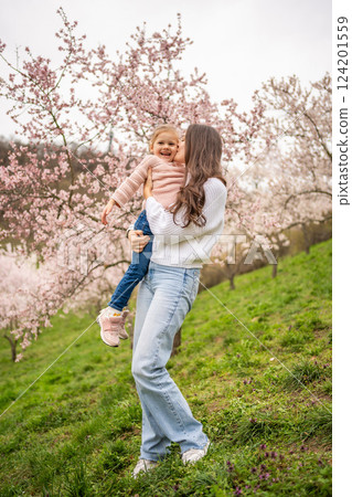 Young woman with little daughter in a blooming pink and white garden Petrin in Prague, spring time in Europe Young woman with little daughter in a blooming pink and white garden Petrin in Prague, spring time in Europe 124201559