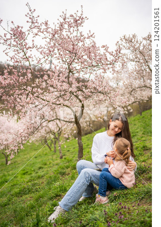 Young woman with little daughter in a blooming pink and white garden Petrin in Prague, spring time in Europe Young woman with little daughter in a blooming pink and white garden Petrin in Prague, spring time in Europe 124201561