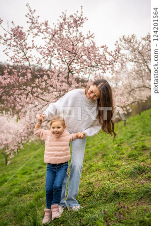 Young woman with little daughter in a blooming pink and white garden Petrin in Prague, spring time in Europe Young woman with little daughter in a blooming pink and white garden Petrin in Prague, spring time in Europe 124201564