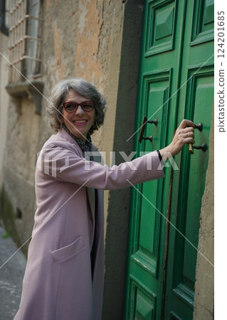 Woman Smiling While Opening a Green Door Woman Smiling While Opening a Green Door 124201685