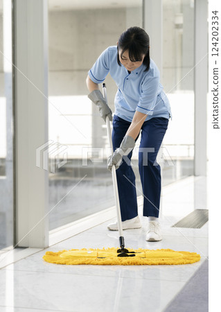 Image of building cleaning: Middle-aged female cleaning staff mopping the floor 124202334