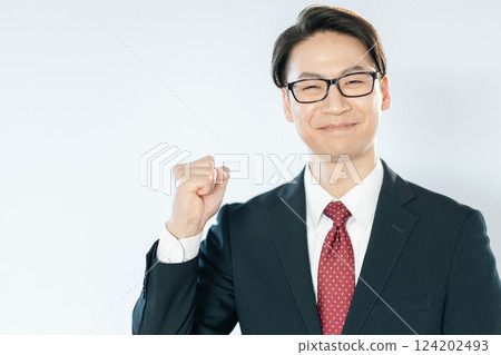 A businessman posing with his fist in the air while looking at the camera 124202493