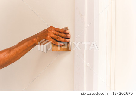Worker hand polishing a wall with sandpaper. Worker hand polishing a wall with sandpaper. 124202679