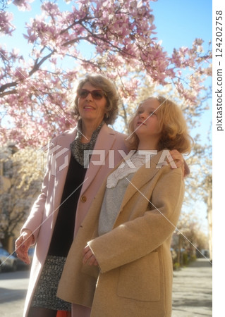 Grandmother and Granddaughter by Blooming Magnolia Tree 124202758