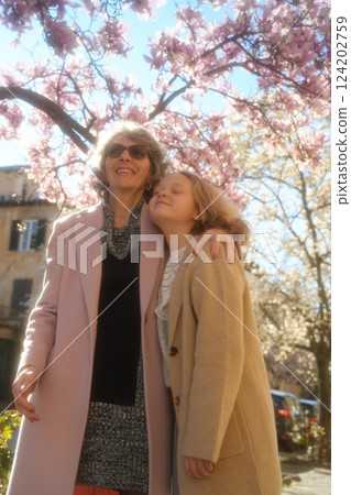 Grandmother and Granddaughter Embracing Under Magnolia Trees 124202759