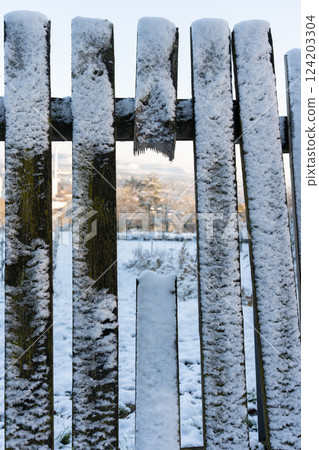 Wooden fence covered with snow, close-up. 124203304