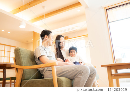 Aerial view of a family of three relaxing in the living room Aerial view of a family of three relaxing in the living room 124203929