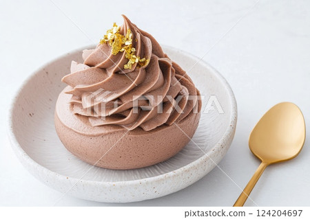 Decadent chocolate mousse topped with gold flakes served in a white ceramic bowl 124204697