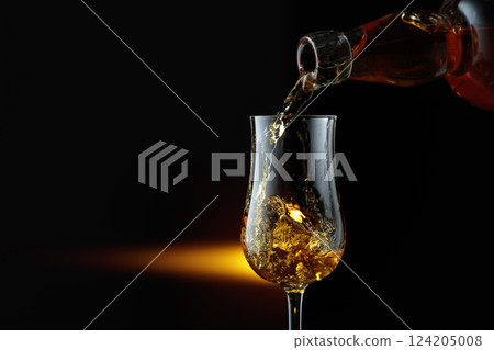 Rum being poured from a bottle into a glass. 124205008