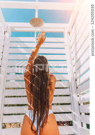 Woman Shower Beach Outdoor Summer: rinsing sand off after sunbathing in white beach shower. 124205030