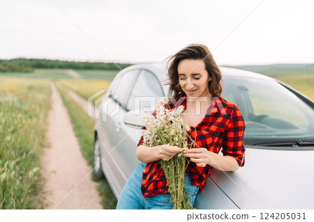 A woman is sitting on the side of a road with a bouquet of flowers in her hand A woman is sitting on the side of a road with a bouquet of flowers in her hand 124205031
