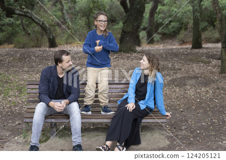 Happy family enjoying free time in park with child standing on bench Happy family enjoying free time in park with child standing on bench 124205121